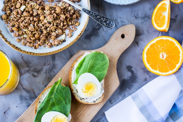 Здоровый сытный завтрак - мюсли, бутерброд с яйцом, кофе, апельсином и соком