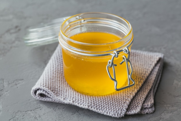 Healthy homemade Ghee or clarified butter in a jar on grey concrete background. Healthy Ayurveda food concept.