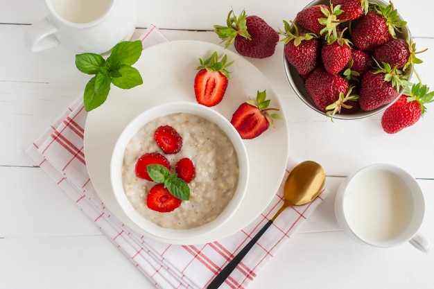 Healthy homemade oatmeal with fresh strawberries on white marble background. Top view.