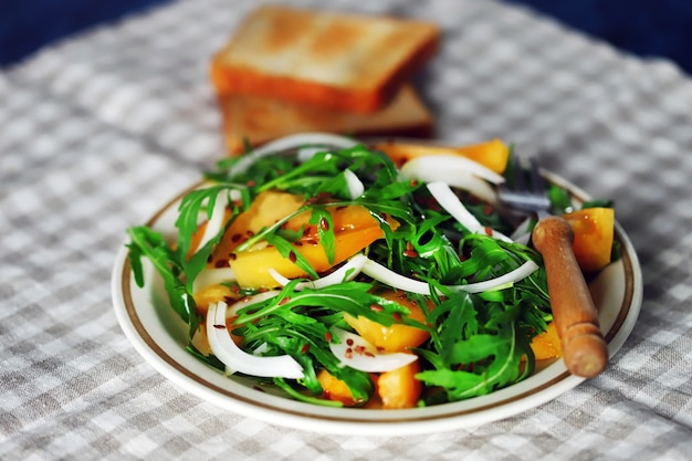 Healthy homemade salad with arugula and yellow tomato on a plate.