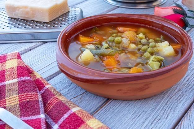 Foto zuppa di verdure fatta in casa sana fresca e pronta da mangiare - su tavola di legno, parmigiano