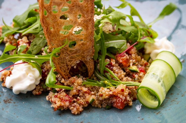 Healthy Italian salad of quinoa seeds, tomatoes and arugula with cream cheese and toast. Haute cuisine in the restaurant on the street terrace