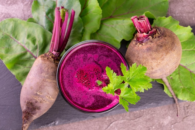 Healthy juice from beets in a glass on a black slate board. Flat lay.