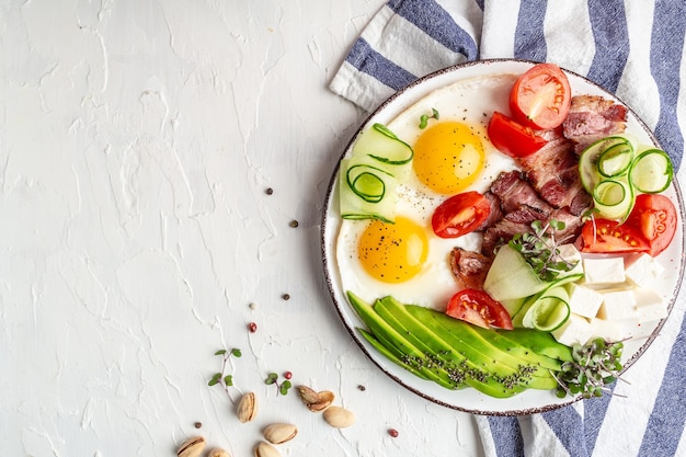 Healthy keto breakfast egg, avocado, cheese, bacon and fresh salad