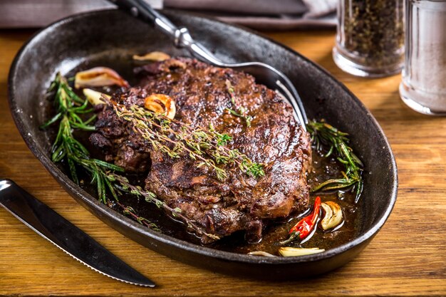 Healthy lean grilled medium-rare steak and vegetables with whiskey glass and a spice in a rustic pub or tavern. Food-styling