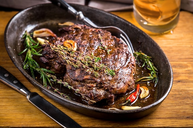 Healthy lean grilled medium-rare steak and vegetables with whiskey glass and a spice in a rustic pub or tavern. Food-styling