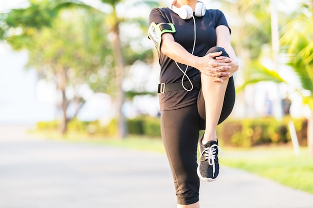 Здоровая жизнь. Азиатский фитнес женщина бегун растяжения ноги перед запуском