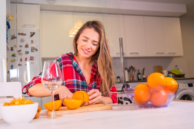 Stile di vita sano, donna caucasica bionda con un succo d'arancia fresco per la colazione nella sua cucina