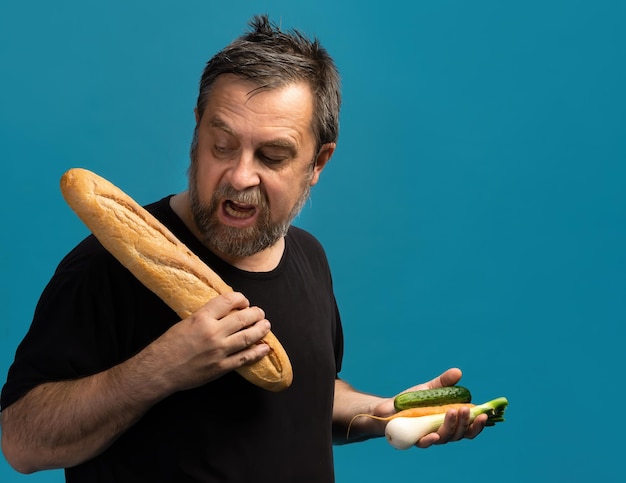 Healthy lifestyle concept. Hard choise. What is better bread or vegetables. A middle-aged man in a black T-shirt holds apple in one hand and bread in the other