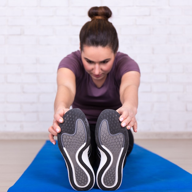 Healthy lifestyle concept - young woman doing stretching exercise on yoga mat