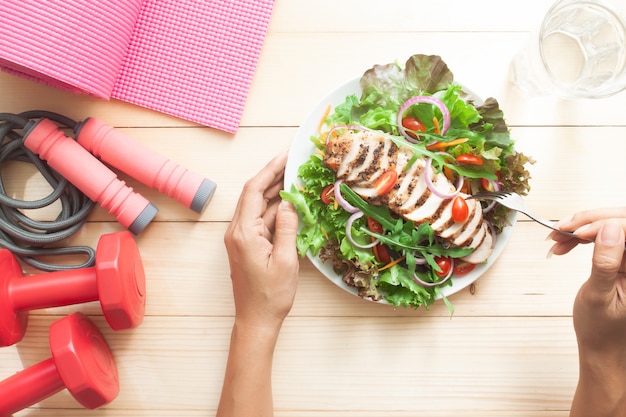 Stile di vita sano e concetto di dieta, tavola di legno di vista superiore con il piatto di insalata e le attrezzature di forma fisica