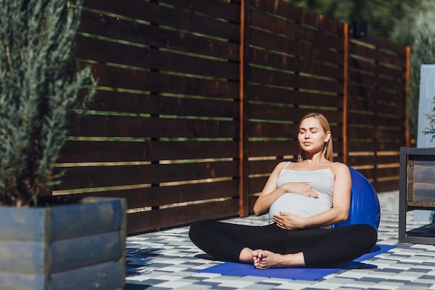 Foto stile di vita sano durante la gravidanza. una ragazza incinta medita nella posizione del loto