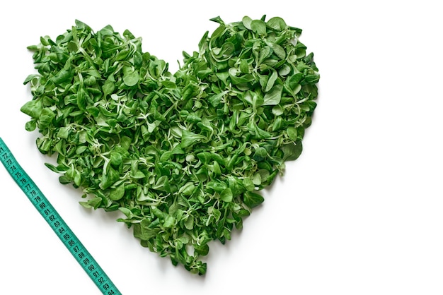 건강한 생활. 그림 중앙에 있는 시금치 잎과 측정 테이프의 심장. 신선한 샐러드 잎
