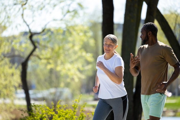 健康的なライフスタイル 成熟したカップルが朝に公園でジョギングをしています