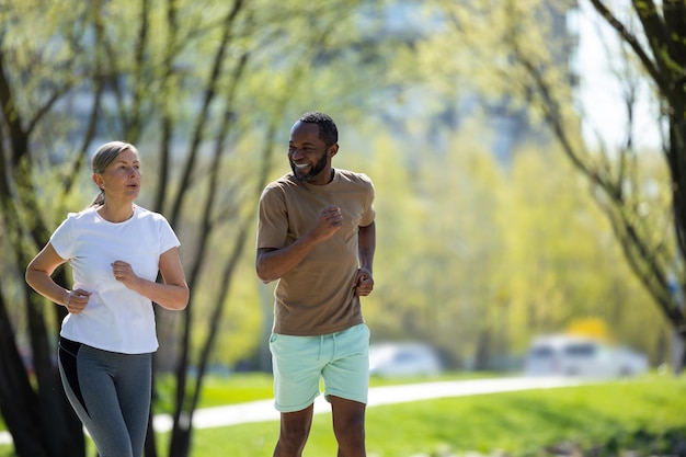 健康的なライフスタイル 成熟したカップルが朝に公園でジョギングをしています