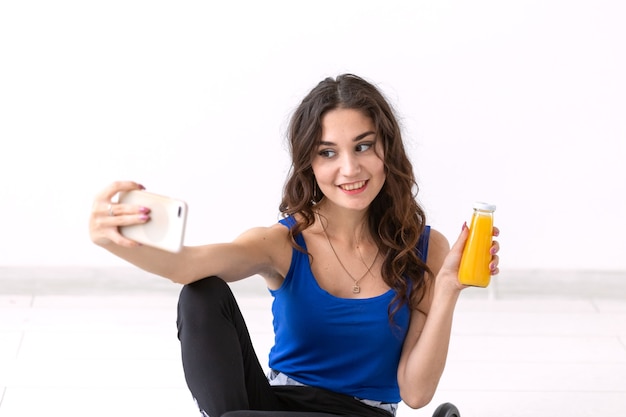 Healthy lifestyle, people and sport concept. Woman taking selfie and holding juice.