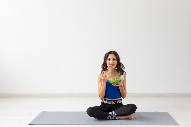 Healthy lifestyle, people and sport concept. Yoga woman with a bowl of vegetable salad.