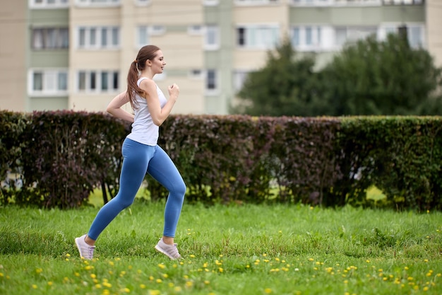 Healthy lifestyle in residential area woman from an apartment\
building on outskirts of city is jogging in park area