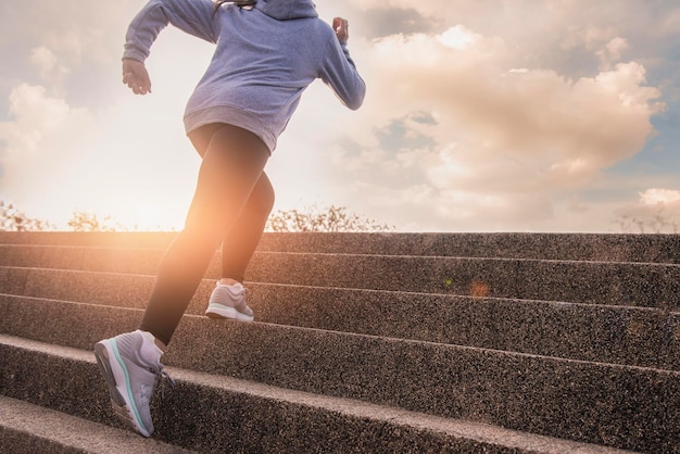 Фото Спортивная женщина здорового образа жизни бежит вверх по каменной лестнице. интервальная тренировка. спортивная женщина тренируется, бегая по лестнице на улице для утренней тренировки.