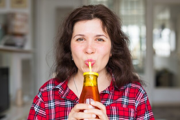 Здоровый образ жизни, витаминные напитки и концепция диеты - крупным планом счастливая женщина пьет сок дома