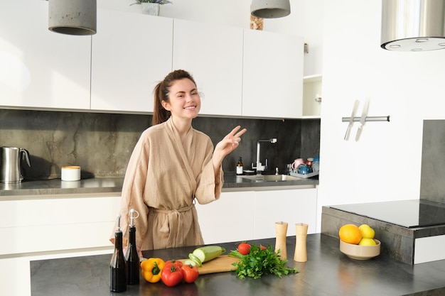 Healthy lifestyle young woman in bathrobe preparing food chopping vegetables cooking dinner on