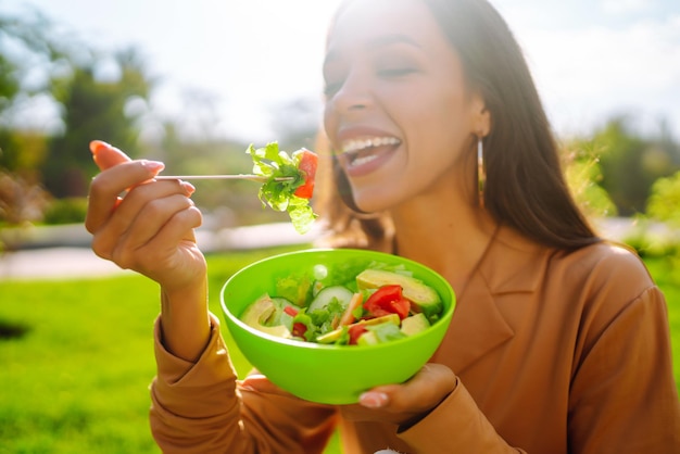 健康的なライフスタイル 晴れた日に野外で新鮮な野菜サラダを食べている若い女性 ベジタリアン