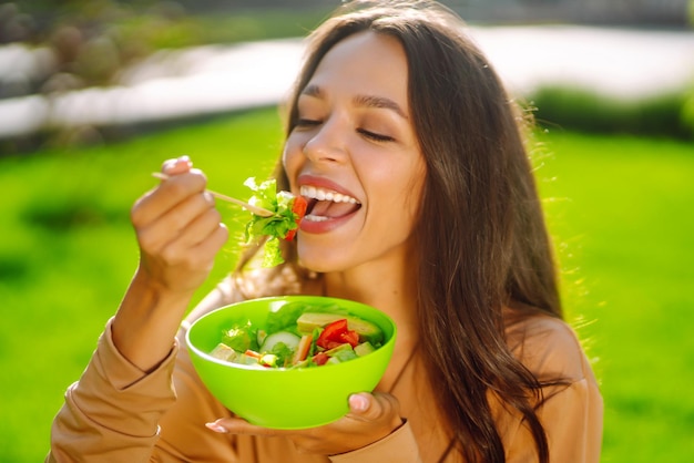 Photo healthy lifestyle young woman eating fresh vegetable salad on sunny day outdoor vegetarian