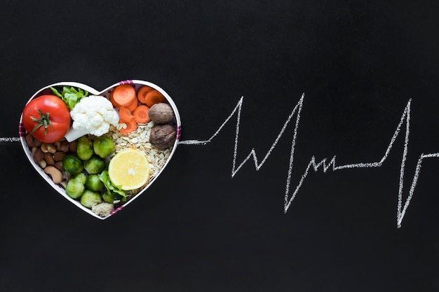 Photo healthy living concept with vegetables arranged in heartshape as an ecg life line on black background