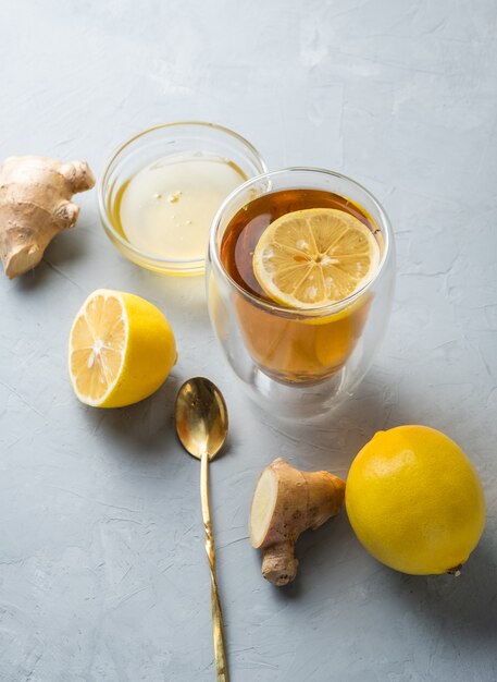 Foto tè al miele al limone e tè alle erbe con radice di zenzero su una superficie grigia