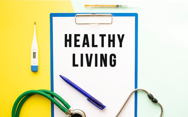 HEALTHY LIVING text on a letterhead in a medical folder on a beautiful background. Stethoscope, thermometer and pen.