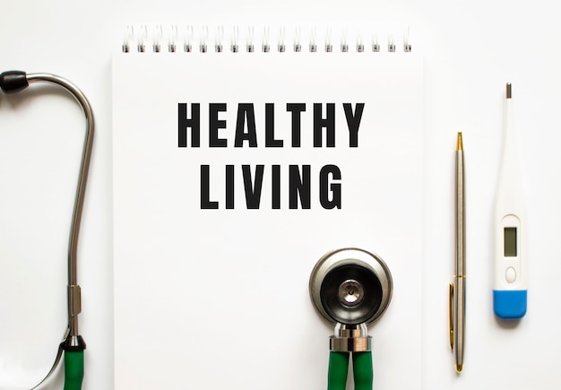 Photo healthy living text written in a notebook lying on a desk and a stethoscope.