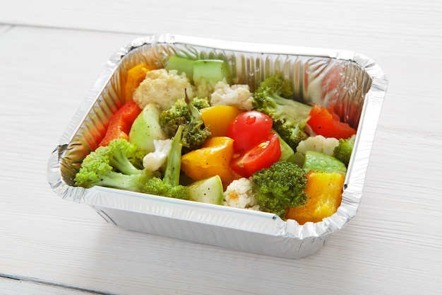 Healthy lunch and diet concept. Take away of food. Boiled vegetables such as cauliflower, broccoli, cherry tomatoes and peppers at white wood