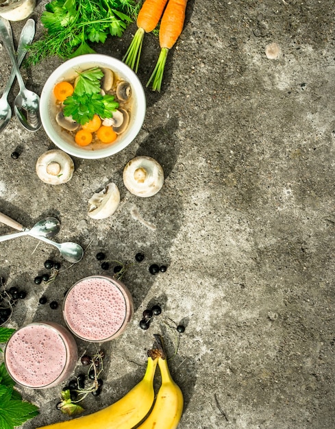 Pranzo sano. zuppa di funghi con verdure e frullato di frutta. su fondo rustico.