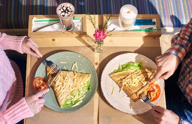 野菜とチーズを添えたヘルシーなランチ。おいしいランチオムレツとコーヒーを飲んでいるカップル。クロップドトップビュー。