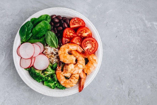 Healthy lunch Shrimp Burrito Bowl with brown rice spinach radish black beans tomato and broccoli