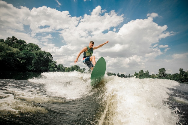 Healthy male rides the waves in a summer river