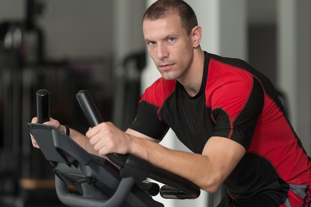 Uomo in buona salute sulla bicicletta nella palestra di forma fisica