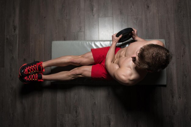 Фото Здоровый мужчина делает приседания на полу с весами