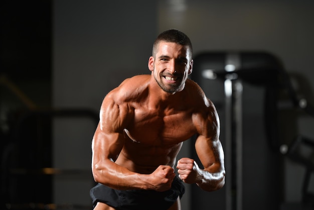 Healthy Man Standing Strong In The Gym And Flexing Muscles  Muscular Athletic Bodybuilder Fitness Model Posing After Exercises