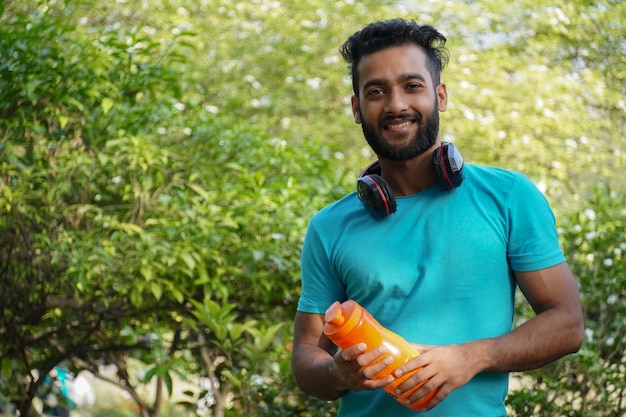 Uomo sano con bevanda proteica nello shaker al parco al mattino