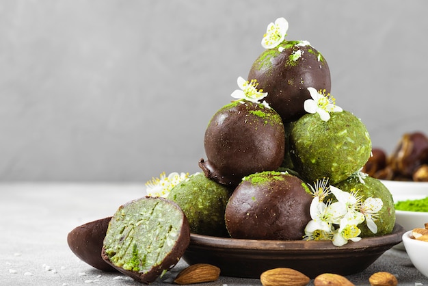 Healthy matcha bliss energy balls in chocolate glaze with flowers, dates, coconut and nuts. Vegan snack dessert. close up