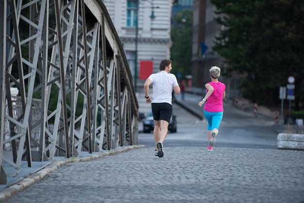 healthy mature couple jogging in the city  at early morning with sunrise in background