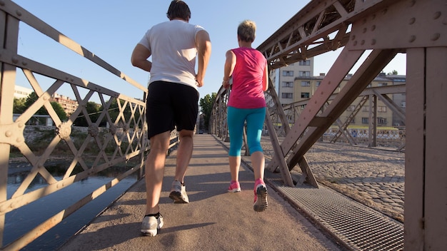 healthy mature couple jogging in the city  at early morning with sunrise in background