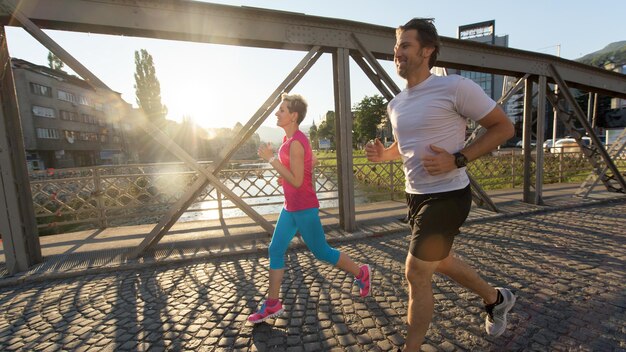 healthy mature couple jogging in the city  at early morning with sunrise in background