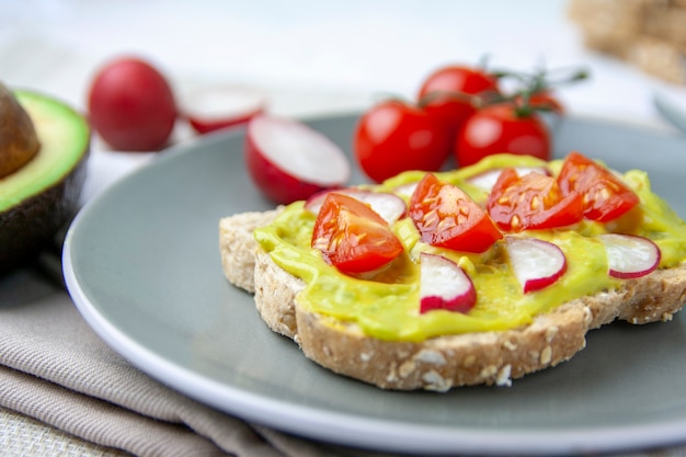 Healthy meal with toast with avocado, tomato and radish on a plate and the ingredients