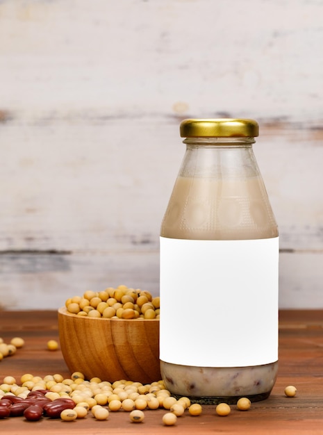 Healthy milk nourishment drink from organic beans extract in glass cup and bottle as advertising beverage product for natural vegan breakfast. Vitamin therapy from ingredient recipe of legume grains.