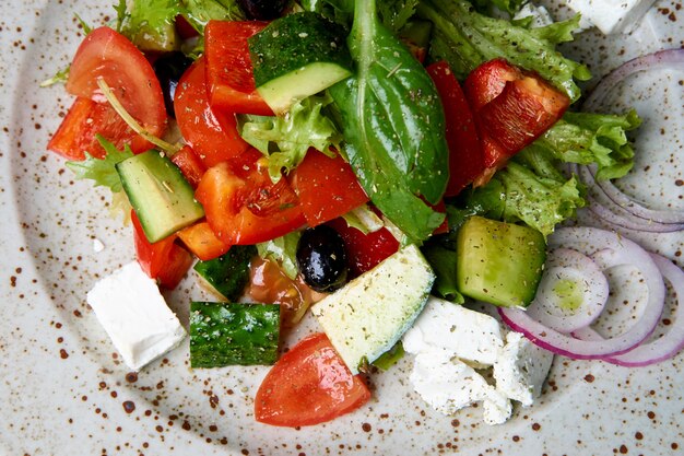 Healthy mixed salad with greens, cucumber, onion, tomatoes and feta cheese.