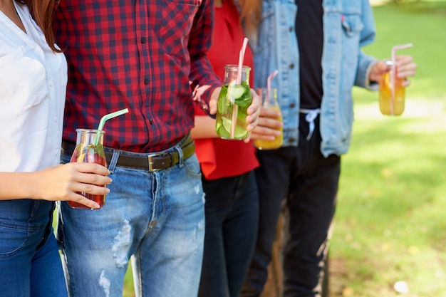 건강한 영양. 녹색 자연 배경에 신선한 주스 해독을 마시는 친구. 청소년 라이프 스타일, 채식주의 식단, 피트니스 음식, 성공적인 체중 감량 개념