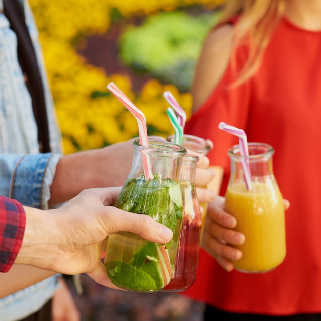 Alimentazione sana. amici che bevono succo di disintossicazione fresca sullo sfondo della natura verde green