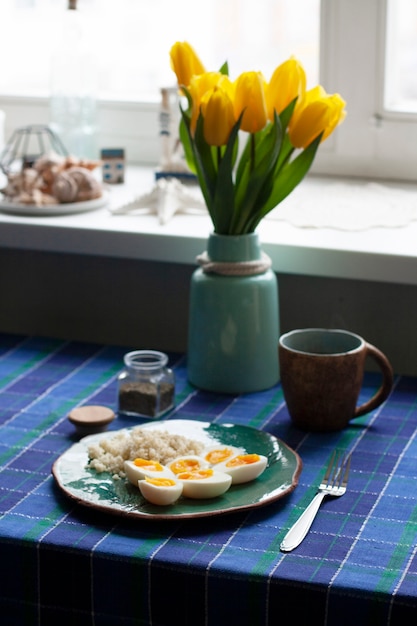 A healthy and nutritious breakfast: a cup of tea; a plate of hardboilde eggs with cuscus.